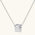 Close-up of a silver-toned molten cube pendant necklace with organic flowing texture on a minimalist chain