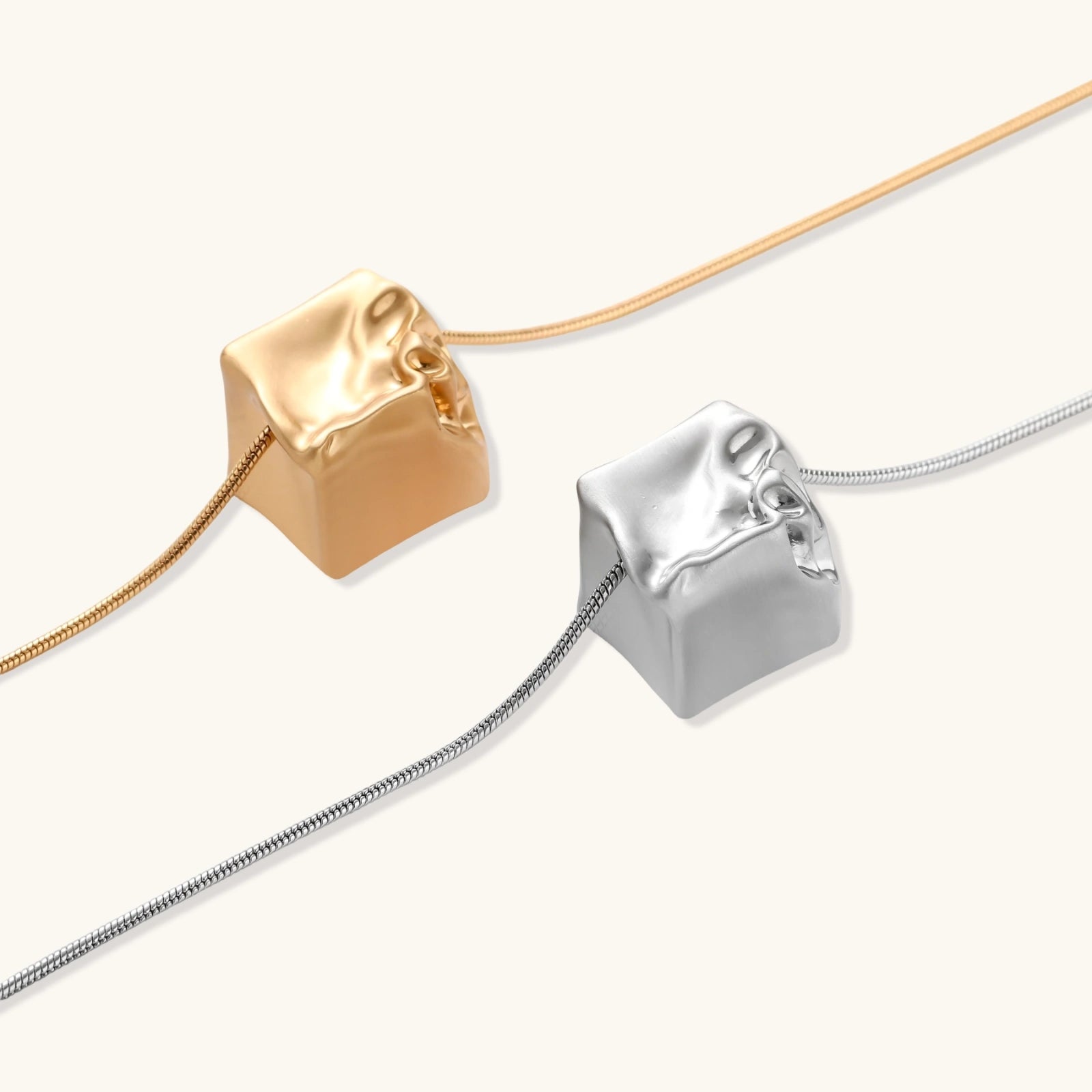 Close-up of a silver-toned molten cube pendant necklace with organic flowing texture on a minimalist chain