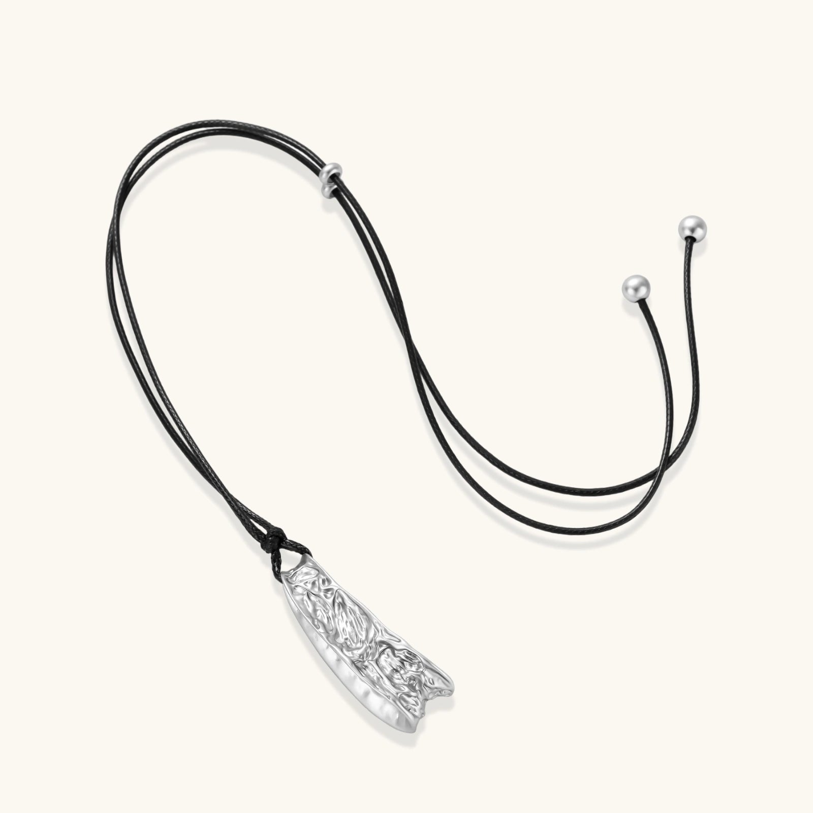 Adjustable black cord necklace with intricate silver-toned pendant featuring ornamental relief patterns and bead details.