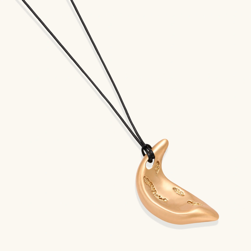Gold crescent moon pendant with paisley patterns on adjustable black cord with brass beads