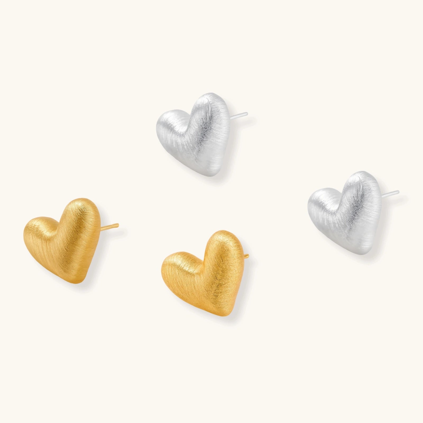 Pair of brushed platinum-plated 925 sterling silver puffy heart stud earrings on a cream background.
