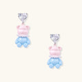 Cute pink teddy bear dangle earrings with clear crystal hearts and blue enamel details on white background.