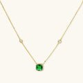 Delicate gold chain necklace featuring square emerald pendant with crystal halo and station accents