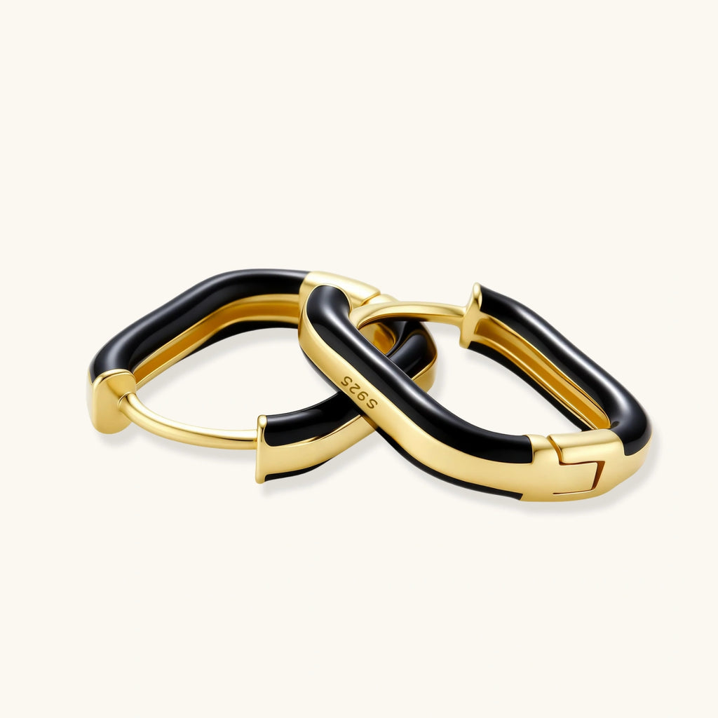 Modern hoop earrings with gold-plated and black sections, featuring hinged closure on white background.