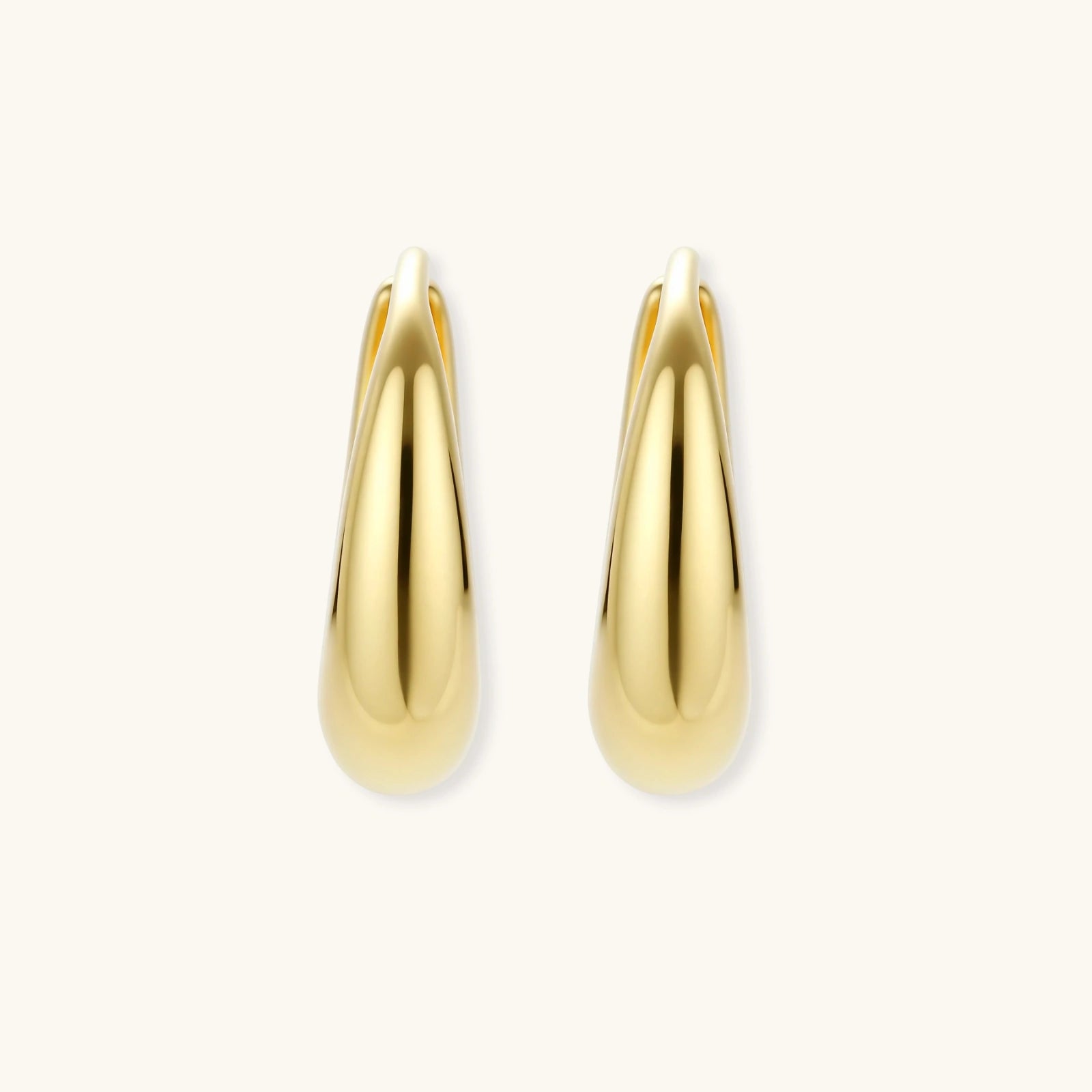 Chunky gold-plated sterling silver huggie hoop earrings with hinged closure mechanism on cream background.