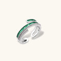Modern adjustable ring with green baguette stones and clear crystals in parallel bands on white background.