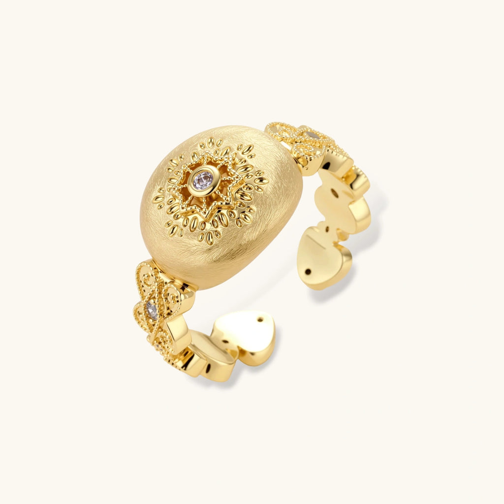 Ornate gold-plated ring with detailed engravings and central zirconia stone on adjustable band