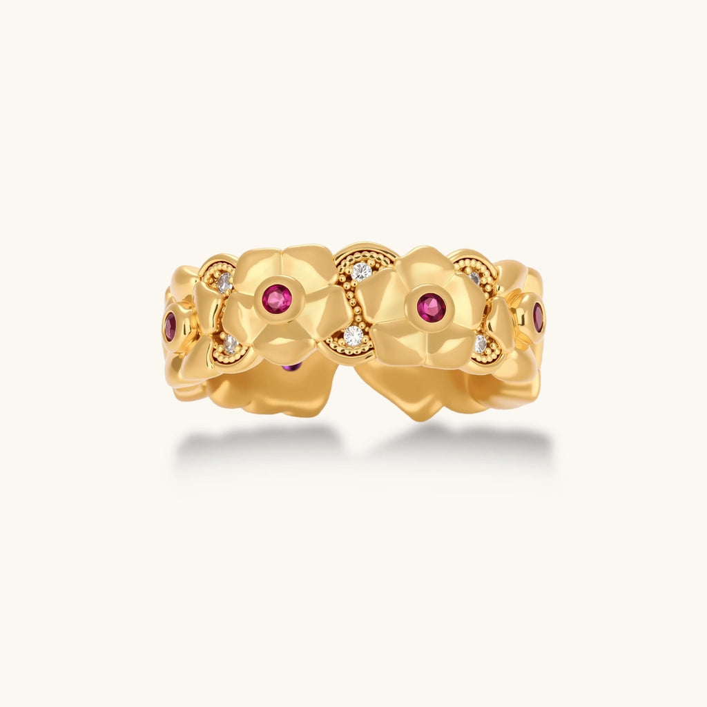 Adjustable gold-plated ring with burgundy zirconia centered flowers and crystal accents on cream background.
