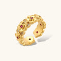 Adjustable gold-plated ring with burgundy zirconia centered flowers and crystal accents on cream background.
