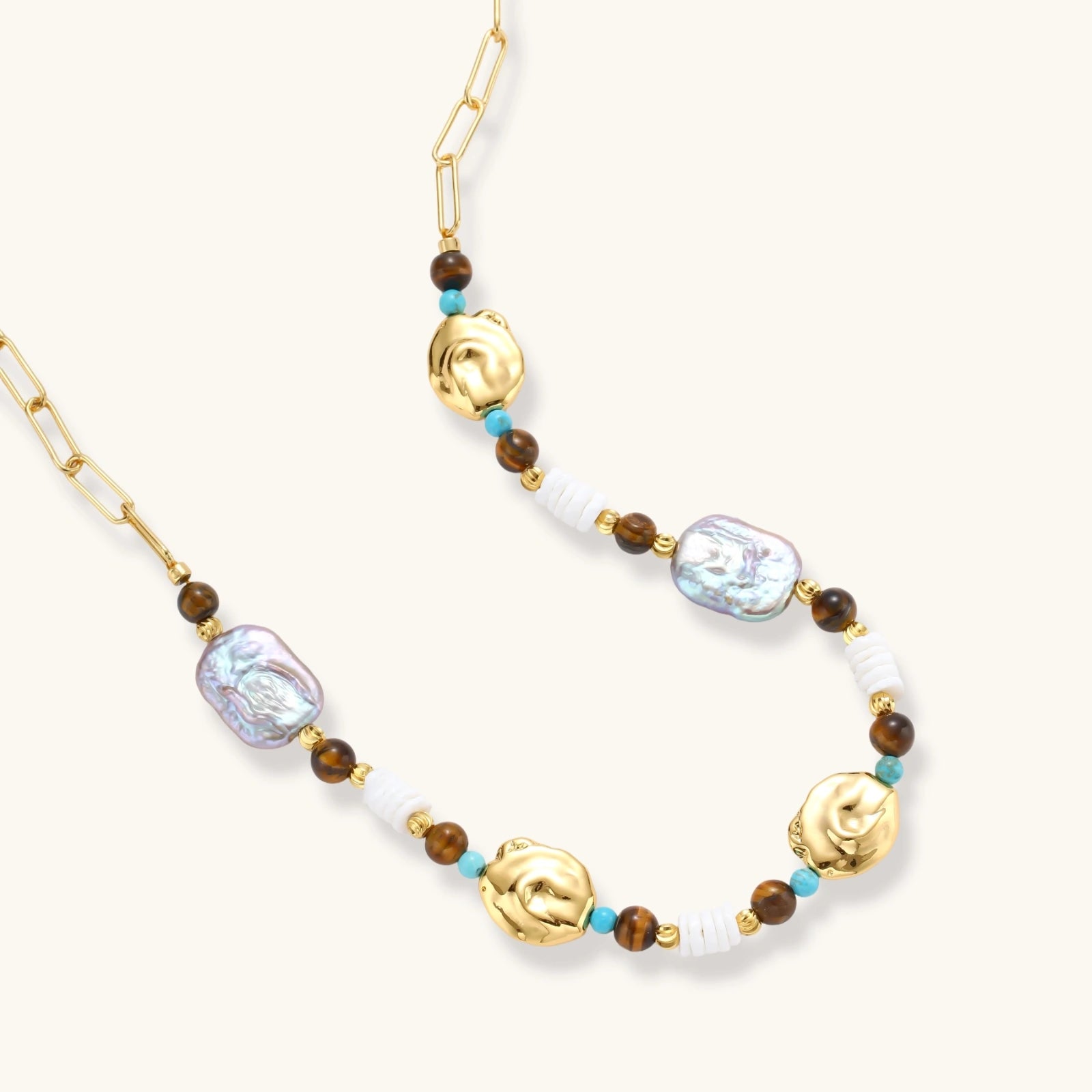 Gold-plated beaded necklace with iridescent baroque pearls, turquoise stones, and brown natural beads on neutral background.