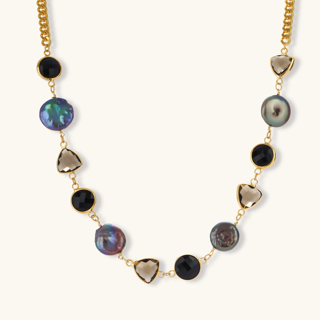 18k gold-plated chain necklace featuring lustrous baroque pearls, black onyx rounds, and smoky quartz triangular stones on white background.