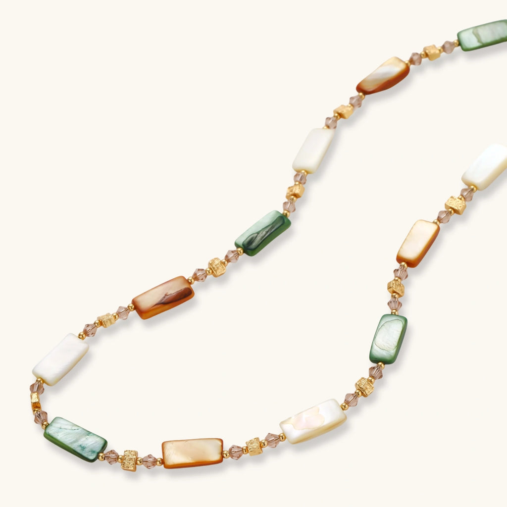 Adjustable gold-plated necklace with natural shell beads in green, amber, and cream tones on neutral background.