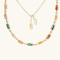 Adjustable gold-plated necklace with natural shell beads in green, amber, and cream tones on neutral background.