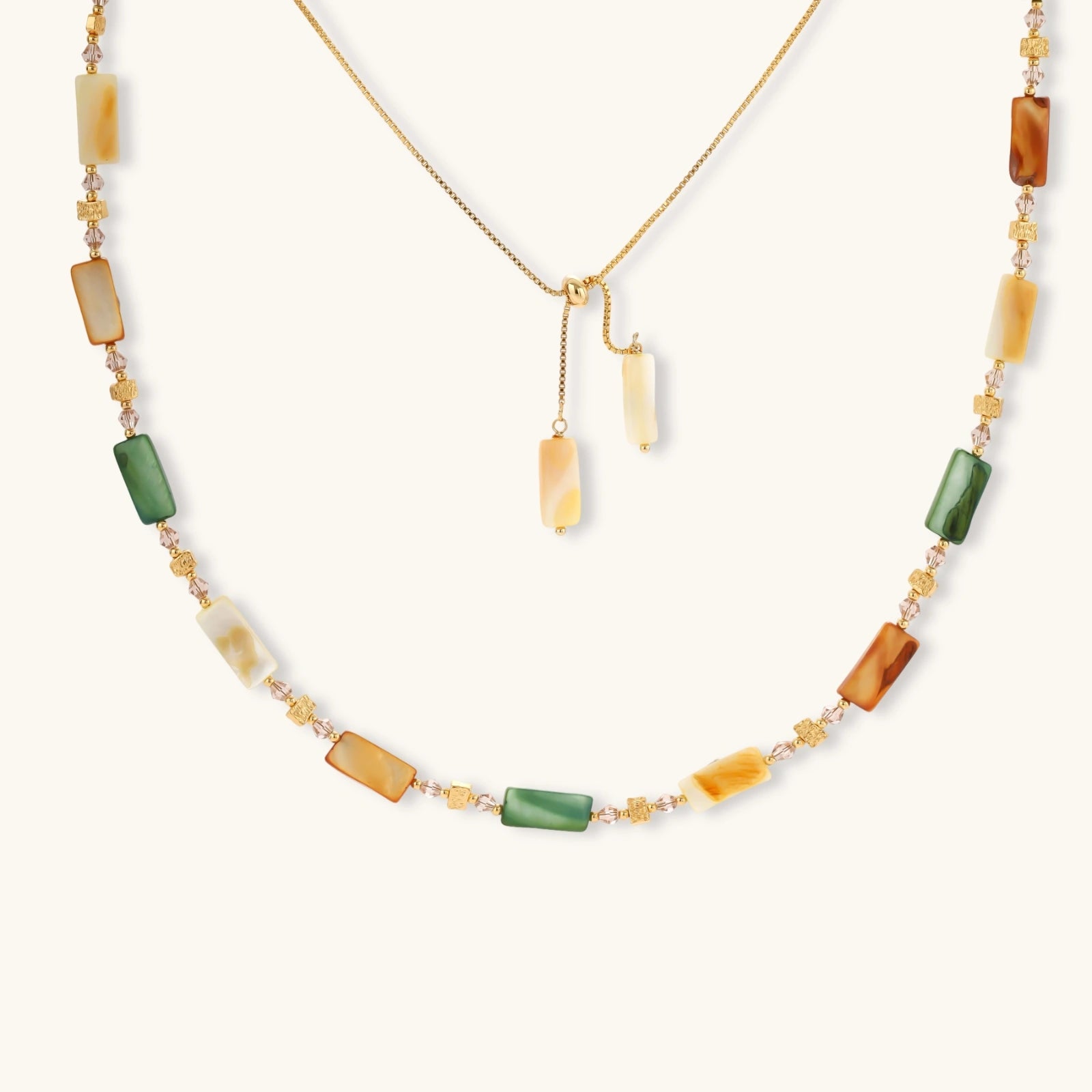 Adjustable gold-plated necklace with natural shell beads in green, amber, and cream tones on neutral background.