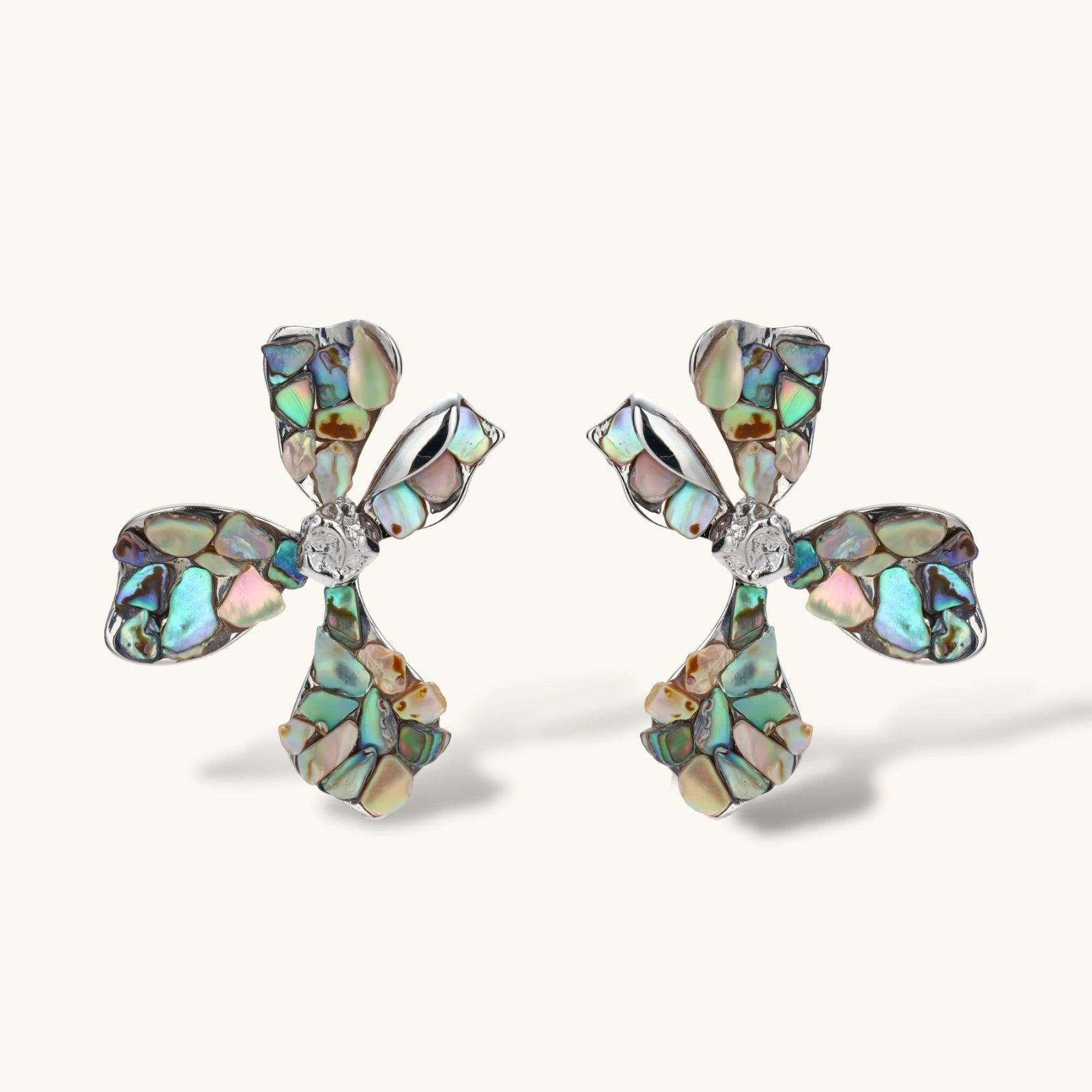 Cross-shaped stud earrings with iridescent abalone shell mosaic in blues and greens, silver-plated setting with crystal center