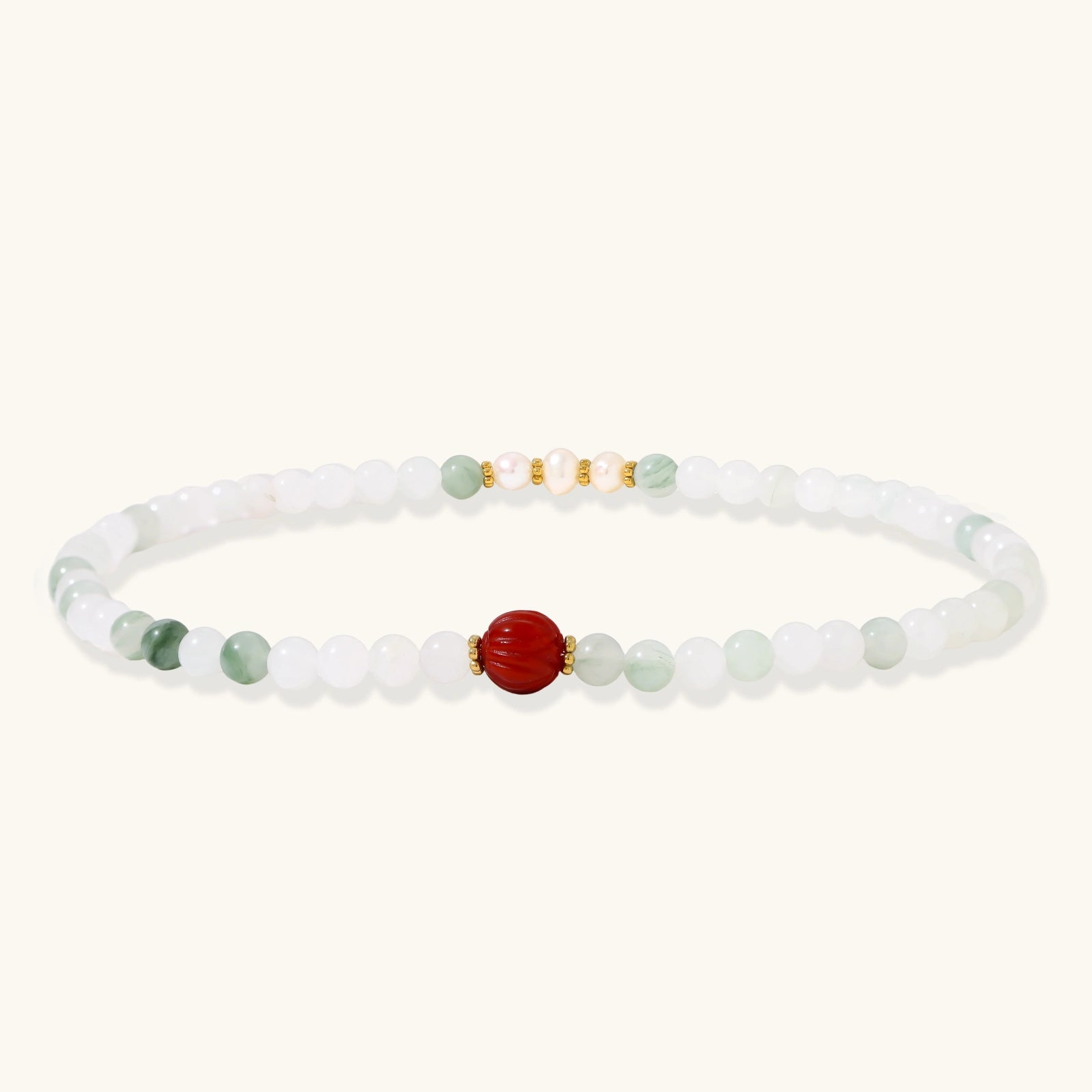 Three layered white beaded bracelets with carved orange agate lotus centerpiece and freshwater pearls on cream background.